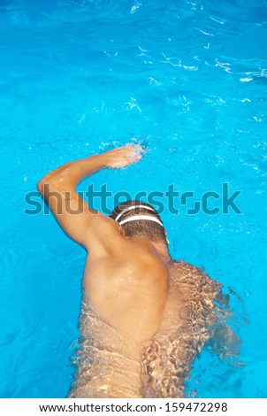 Man swims in the pool with swimming goggles.