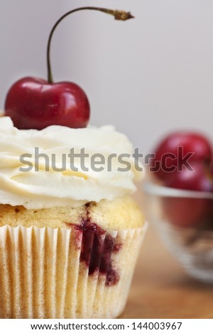 jam cupcake with mascarpone cream cheese topping cherries on table in studio with white background