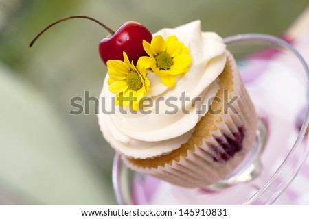 jam cupcake with mascarpone cream cheese topping cherries and flowers in studio with real background