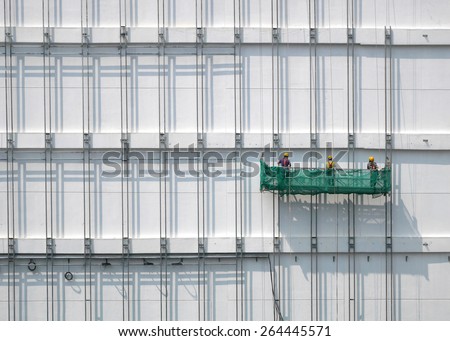 UNDER CONSTRUCTION\
group of construction workers are on duty. they are moving slowly by  suspended work platform.
