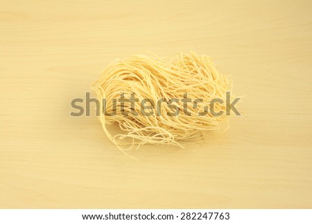 CHINESE NOODLE\
one portion of dried chinese egg noodle on the wood table.