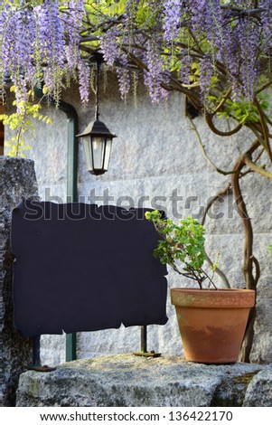 Black board with pendent flowers and stone background. Springtime