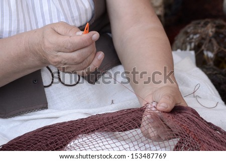 Woman hands creating a net. Needlework, traditional labor.