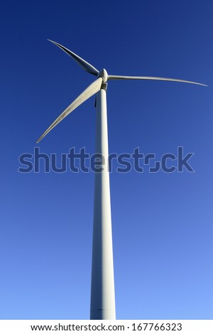 Wind energy business. Wind turbine closeup with blue sky background. Vertical view