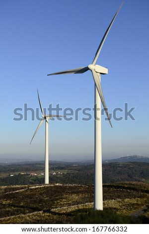 Wind energy business. Wind turbine closeup with blue sky, green grass and village