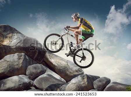 Sport background. Cyclist climbing on a rock.
