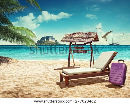Travel. Beach chair and suitcase on sand beach. Concept for rest