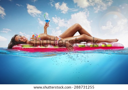 Summer. Vacation. Woman hanging out on air mattress. With underwater part