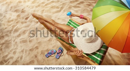 Vacation. Travel. Beautiful young woman relaxing on beach chair with cocktail. Top view