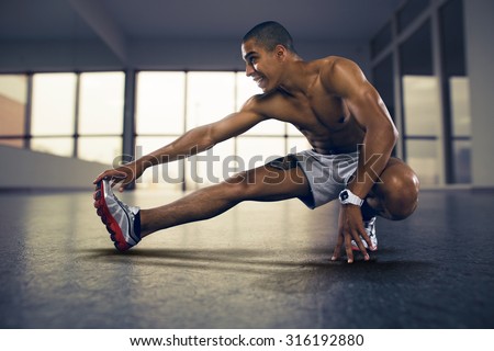 Sports. Man at the gym doing stretching exercises and smiling on the floor