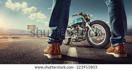 Sport. Biker standing near the motorcycle on an empty road at sunny day. Close view on legs