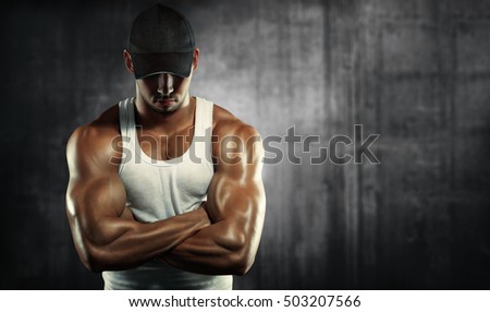 Sports background. Bodybuilding. Strong man  posing on a concrete background