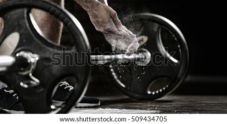 Sports background. Young athlete getting ready for weight lifting training. Powerlifter hand in talc preparing to bench press