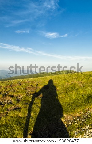 The shadow of a man creates an abstract and symbolic figure in the space of a pristine mountain landscape.