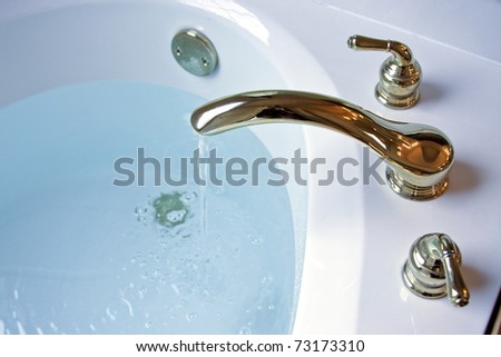 garden tub filling up with water from a gold plated faucet