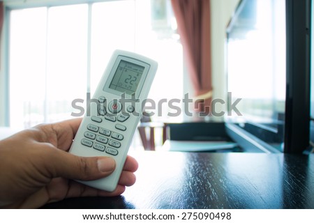 Hand is holding a remote control of air conditioner
