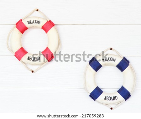White Life buoy with welcome aboard on white wall.