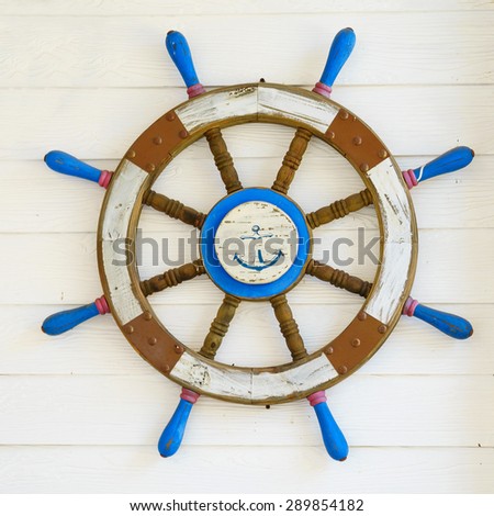Old wooden ship steering wheel on wood wall.