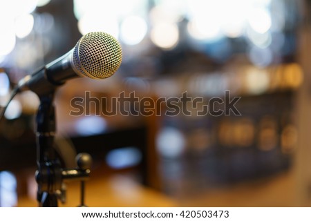 Microphone over the Abstract blurred photo of conference hall or seminar room background.