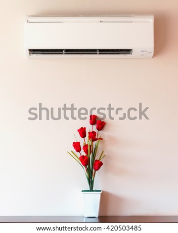 Air conditioner and flower vase with wall.