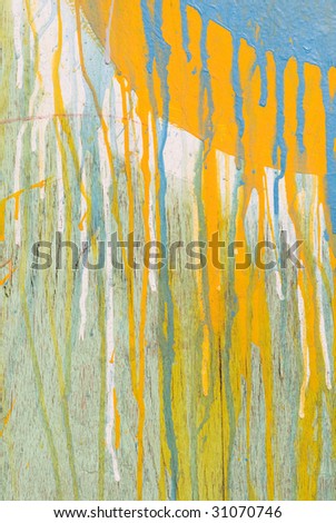 Abstract spattered yellow and blue paint drips down cracked wood background texture