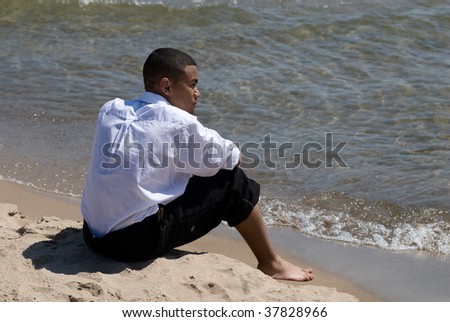 A young African American businessman relaxes on the beach