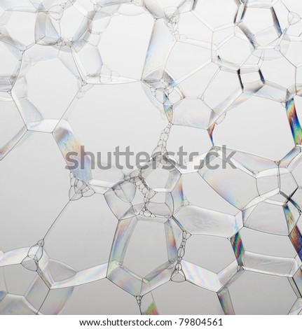 Colorful single plane of soap bubbles on a grey background