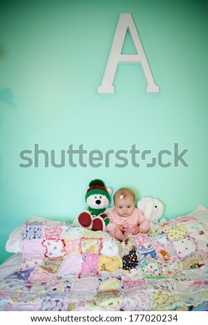 A young infant sits between two stuffed bears