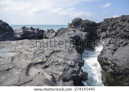 landscape with Spray of water by struck Seawater through tunnel between rocks at the coast near the Olle trail route 16  in Jeju Island, Korea.