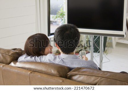 Rear view of young couple watching TV at home