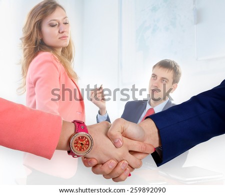 Handshake men and women.Watches at hand. Pink and Blue. Quarrel in the backgro. Focus on handshake/