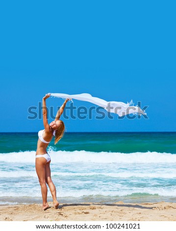 Jumping and dancing happy girl on the beach, fit sporty healthy sexy body in bikini, woman enjoys wind, freedom, vacation, summertime fun concept