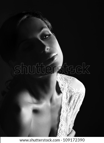 Closeup black&white portrait of sexy woman, beautiful young lady isolated on black background, hot female wearing gorgeous white lace, charming girl in wonderful openwork dress, beauty concept