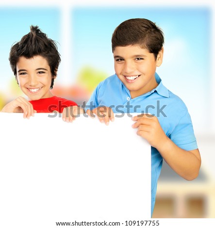Happy schoolboys in the classroom, cheerful preteen boys students holding white blank board with copy space for ad text, teen friends smiling, kids studying at school, children education concept