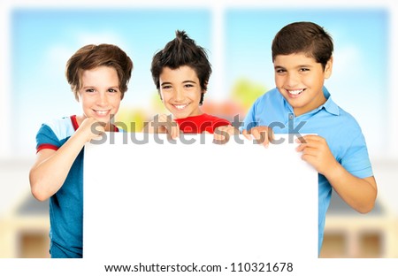 Three boys in classroom holding white clean board, happy children enjoying studying at school, smiling teenager having fun indoors, back to school, best friends concept, love to education