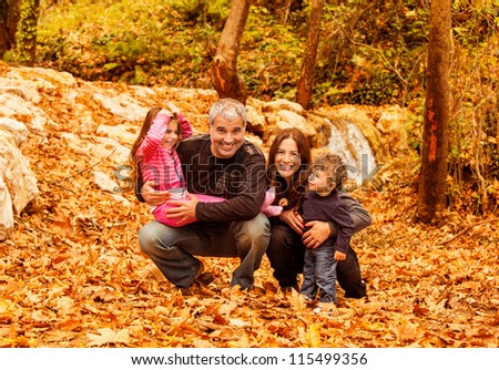 Picture of cheerful young family playing game in autumnal woods, portrait of cute kids with parents in park, autumn holidays, love concept, conceptual of happy family, fall season