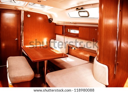 Image of luxury ship interior, comfortable sailboat cabin, expensive wooden design and soft white sofa inside on the yacht, holiday recreation, tourism, travel and vacation concept