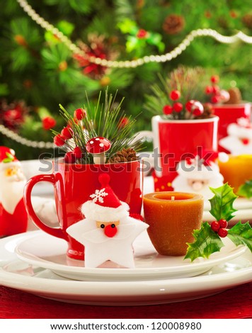 Image of Christmas table decoration, luxury festive utensil over green fir tree background, little red berry twig and star toy decorated table setting in New Year eve, x-mas holiday banquet