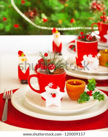 Picture of table setting for winter holidays time, holiday banquet, Christmas celebration, luxury white porcelain dishware on red festive tablecloth, New Year party, decorated evergreen tree