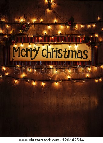 Image of beautiful Christmastime home decoration, Merry Christmas banner hanging on the door decorated with festive lights, x-mas ornament on dark brown grunge background, New Year greeting card