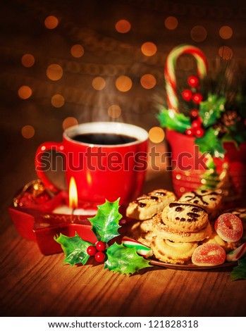 Picture of Christmas sweets still life, red mug with hot chocolate, branch of red berry, homemade gingerbread and tasty candy cane, sweet cookies, brown blur background, New Year dessert
