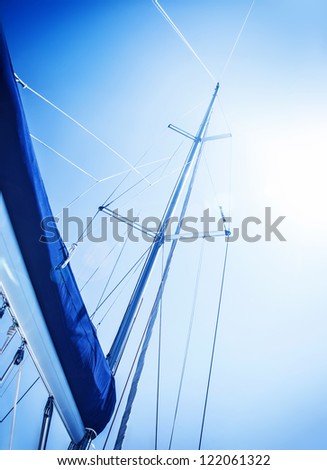 Sailboat in action, big white sail raised over blue clear sky, luxury leisure, summertime activities and extreme sport, boat parts with sun rays, sailing trip vacation, freedom concept