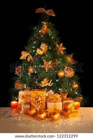 Image of gifts under beautiful Christmas tree isolated on black background, green fir tree decorated with golden balls, stars, angels and garland, different wrapped New Year presents, xmas surprise