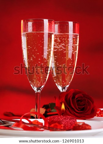 Photo of beautiful Valentine day dinner still life, two glasses for champagne, alcohol beverage, romantic drink, sparkling wine, red rose and candle, festive table setting, love concept