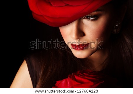Picture of sexy woman with big red rose hat on the head isolated on black background, closeup portrait of stylish girl with flowers bouquet, Valentine day, beauty and styling salon, elegance concept