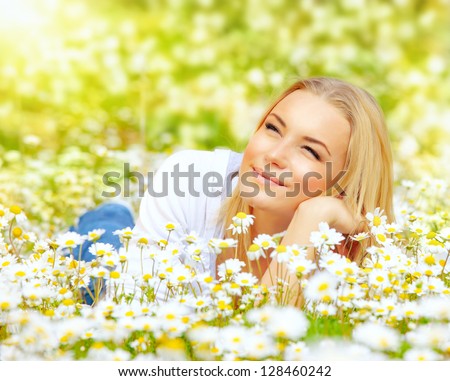 Photo of cute blond female laying down on chamomile field and looking up in sky, sunny day, warm weather, spring holiday and vacation, pretty woman enjoying beautiful nature, daisy field