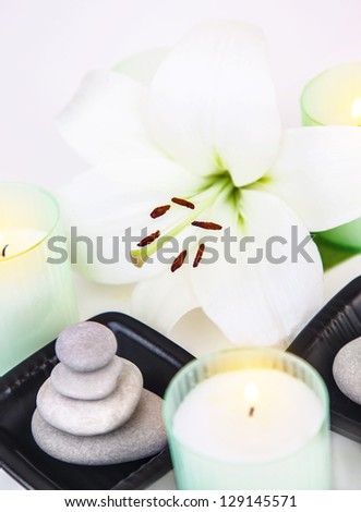 Picture of white lily flower, pebble stones, aromatic candles, closeup of spa still life, spa salon decorations, peace and meditation, herbal massage, zen balance, enjoying dayspa