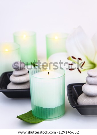 Picture of luxury spa salon, pebble stones in black bowls, white lily flower, warm candlelight, soft focus, zen balance, beauty treatment, herbal bodycare, skin hygiene, harmony and meditation concept