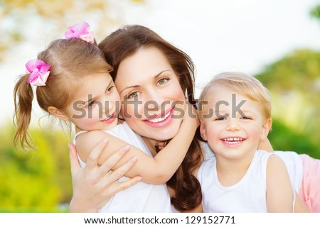 Picture Of Young Mother Hugging Two Little Children, Closeup Portrait Of Happy Family, Cute Brunette Female With Daughter And Son Outdoor In Spring Time, Smiling Faces, Happiness And Love Concept