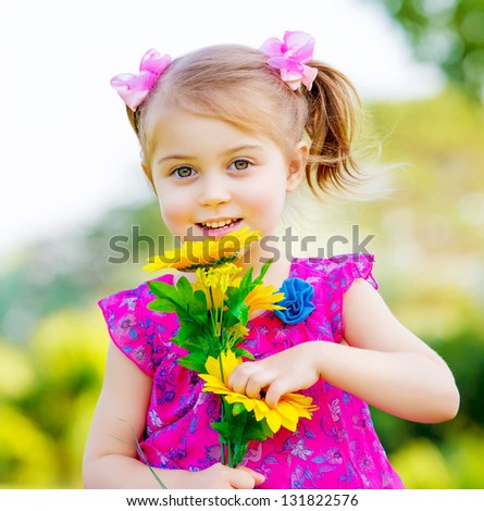 Happy baby girl playing outdoor, cute child holding fresh sunflower flowers, kid having fun in summer park, lovely smiling toddler portrait, enjoying nature of garden